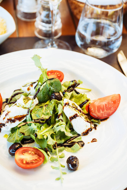 Салат Капрезе за столом. Открытый итальянский ресторан терраса. Концепция летней аутентичной еды. Вертикаль
 - Фото, изображение