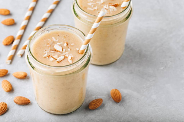 Healthy breakfast. Banana almond smoothie with cinnamon and oat flakes and coconut milk in glass jars - Photo, Image