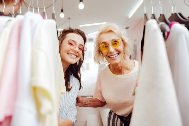 Modern mother and daughter standing near clothes rack - Photo, image