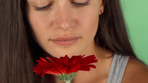 Beautiful young woman smiling joyfully while smelling a flower - Footage, Video