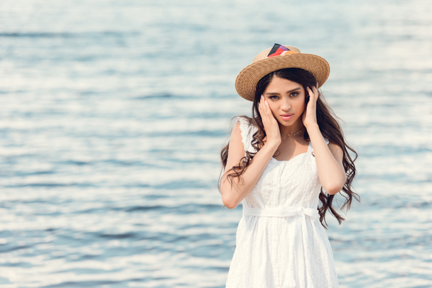 μελαχρινή κοπέλα μελαχρινή σε ψάθινο καπέλο στο παραθαλάσσιο θέρετρο - Φωτογραφία, εικόνα