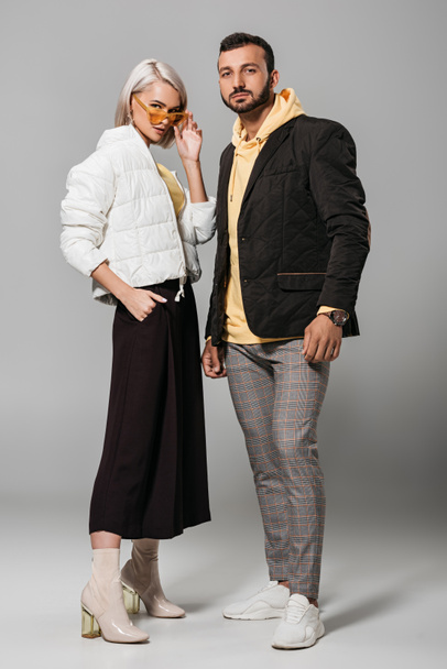 fashionable couple of models in autumn outfits posing on grey background  - Foto, afbeelding