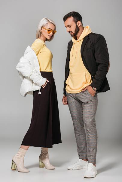 stylish young man and woman in autumn outfits posing on grey background  - Fotografie, Obrázek