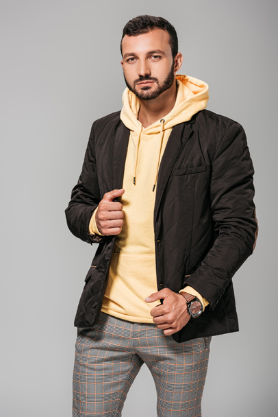 stylish male model in autumn outfit looking at camera on grey background  - Foto, immagini