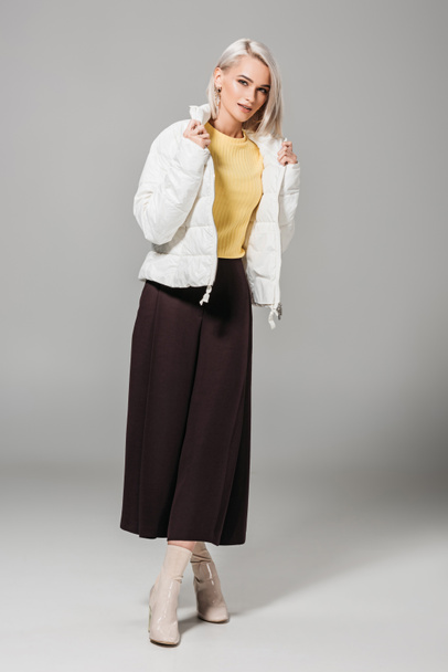 attractive female model in stylish white jacket posing on grey background  - Фото, зображення