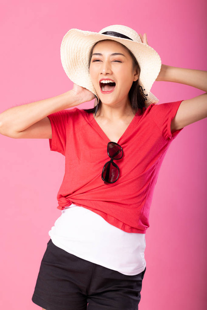 Portrait of a smiling attractive woman in summer outfit and hat posing while standing and looking at camera isolated over pink background. - Φωτογραφία, εικόνα