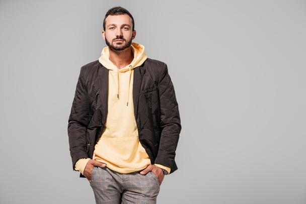 serious male model in stylish autumn outfit looking at camera isolated on grey background  - Foto, afbeelding