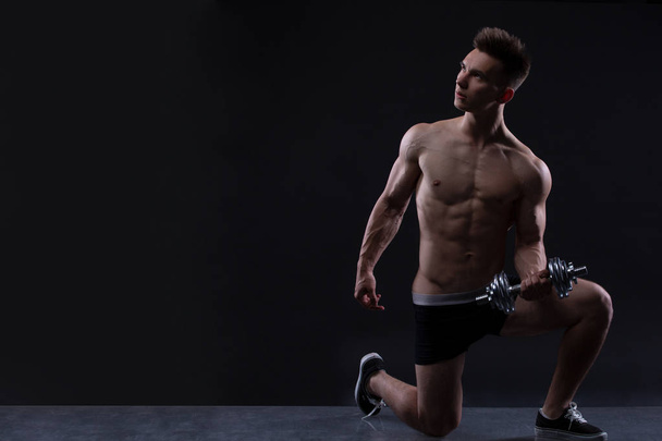 muskulöser Bodybuilder, der Übungen mit Kurzhanteln vor schwarzem Hintergrund macht. Kopierraum - Foto, Bild