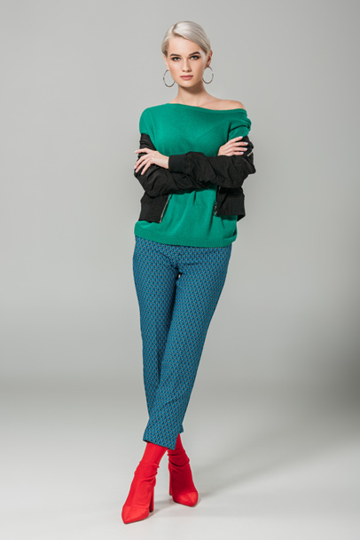 young stylish female model with crossed arms on grey background - Фото, зображення
