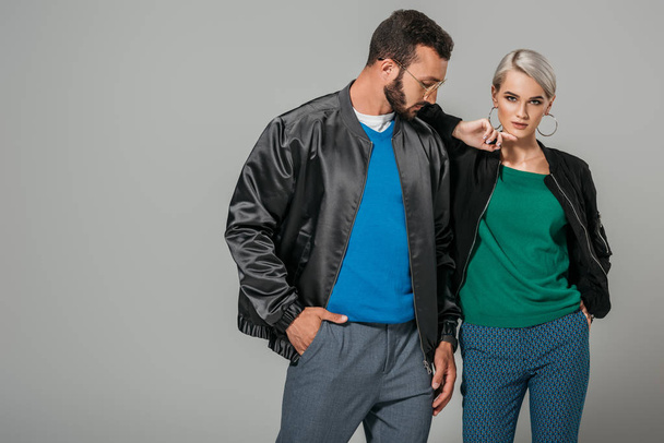 serious couple of models in stylish outfits isolated on grey background  - Foto, imagen
