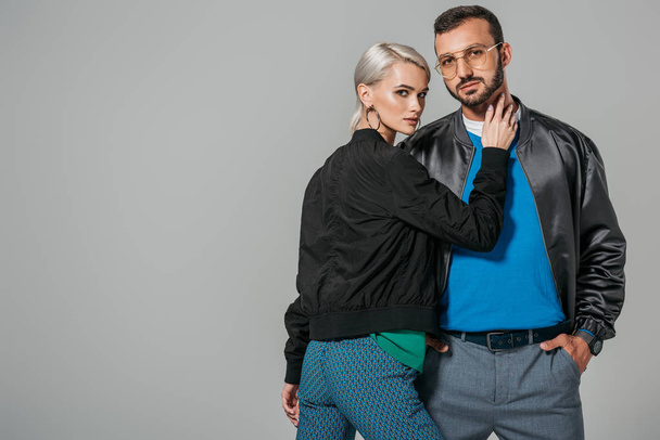 attractive young woman touching neck of stylish boyfriend isolated on grey background  - Zdjęcie, obraz