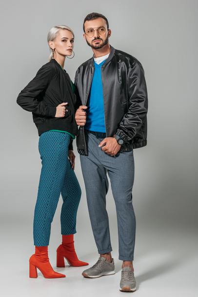 stylish couple of models posing in black jackets on grey background  - Foto, Imagem