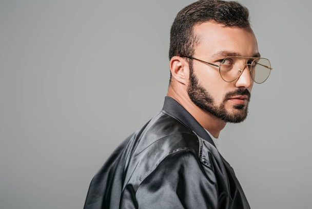 serious handsome man in fashionable eyeglasses looking at camera isolated on grey background - Zdjęcie, obraz