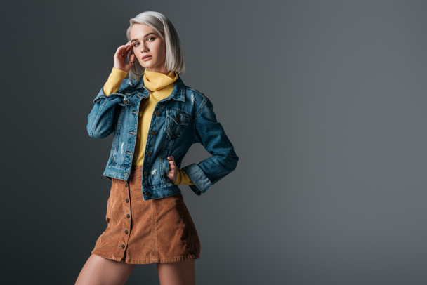 woman posing in yellow turtleneck, trendy corduroy skirt and jeans jacket, isolated on grey - Photo, Image