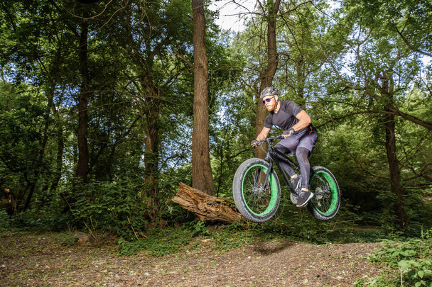 Training a bicyclist in a forest. A brutal man on a fat bike. - 写真・画像