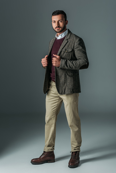 bel modello maschile in posa in pantaloni beige e giacca di tweed, su grigio
 - Foto, immagini