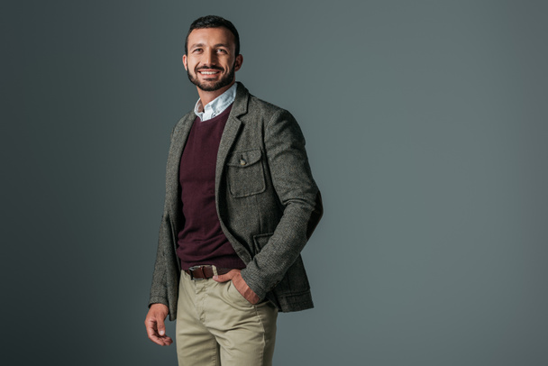 schöner lächelnder Mann posiert in Tweed-Jacke, isoliert auf grau - Foto, Bild