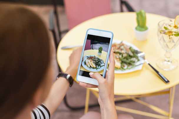 Modern blogger making photo of her summer salad in restaurant - Foto, Imagem