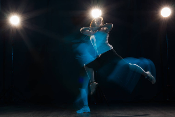 Dancing, sport, beautiful and people concept - young woman dancing in darkness jumped in colourful light - Photo, Image