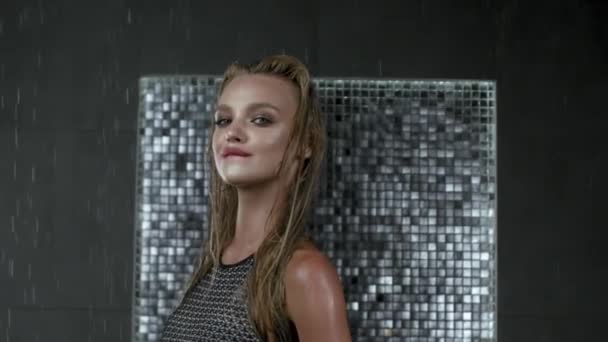 Beautiful sexy blonde girl with wet hair. Posing in a swimsuit in the shower under the drops of water. Slow motion - Záběry, video
