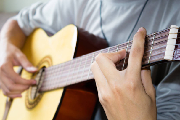 Close up of young man playing guitar. - Фото, зображення