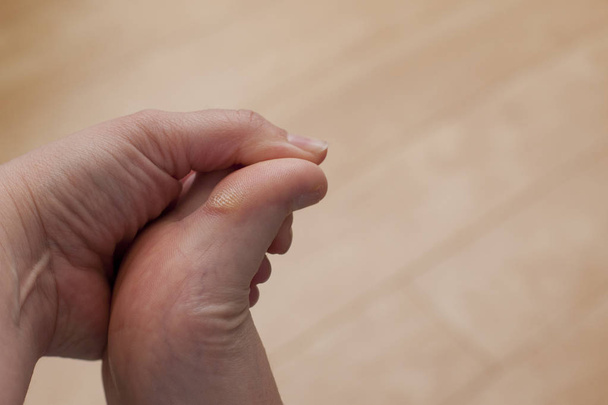  Una mano se aferra a su pie, tocando y mirando un dedo gordo insensible y seco
  - Foto, Imagen