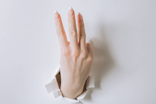 girl hand breaks white paper and shows a gesture. - Valokuva, kuva