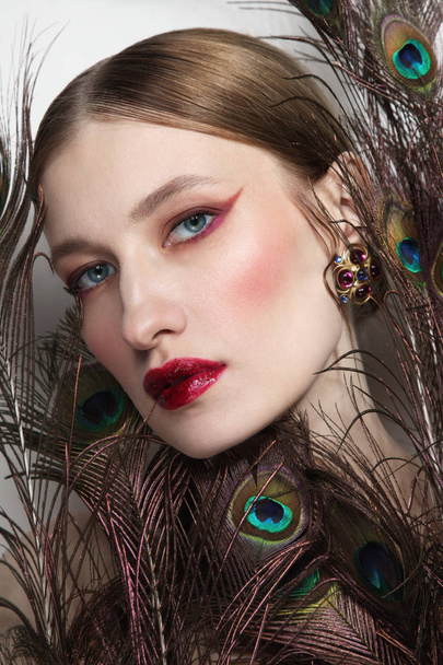 Glamorous portrait of young beautiful woman in peacock feathers - Фото, зображення