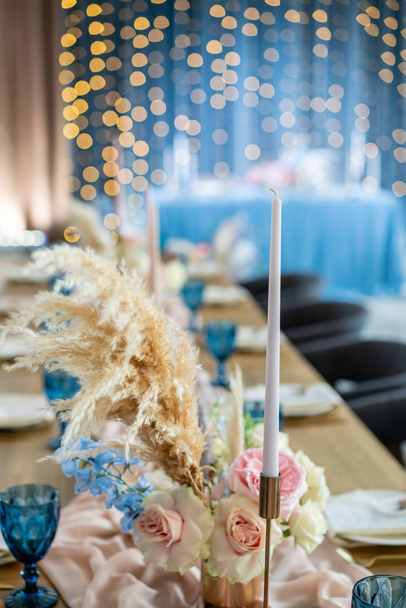 Красива і вишукана прикраса весільного торжества. Банкетний стіл подається з бежево-рожевою скатертиною, тарілками та свічками зі свічками
. - Фото, зображення