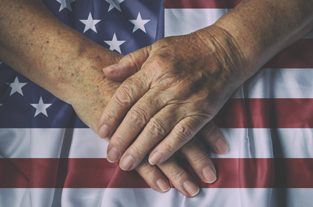 Τα χέρια της παλιάς γυναίκας με αμερικανική σημαία, κάτοψη. - Φωτογραφία, εικόνα