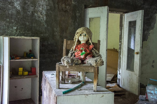 Baby einer Spielzeugpuppe auf einem Bett in einem verlassenen Kindergartengebäude in der Nähe von Pripjat, Tschernobyl, Ukraine - Foto, Bild