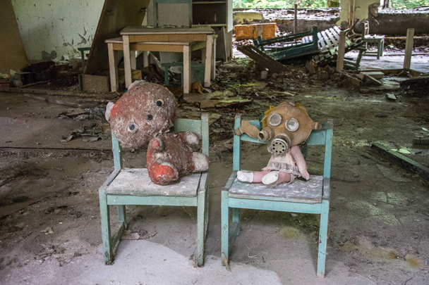 a játék baba baba ült egy ágyon egy elhagyott óvoda épület közelében Pripjaty, Csernobil, Ukrajna - Fotó, kép