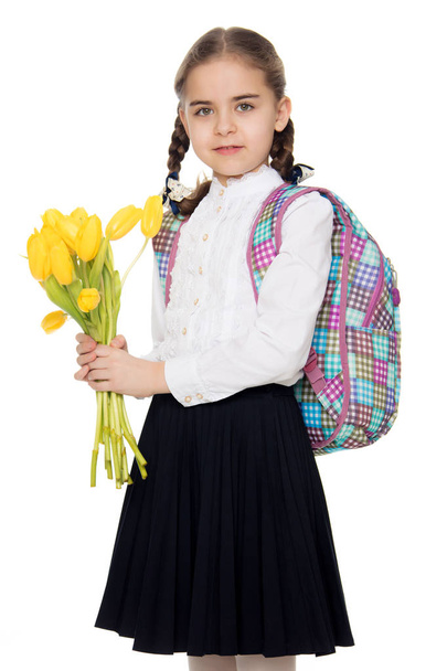 A schoolgirl with a bouquet of flowers and a backpack on her sho - Photo, image