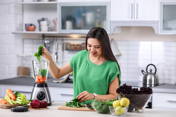 Young woman preparing tasty healthy smoothie at table in kitchen - Foto, Imagen