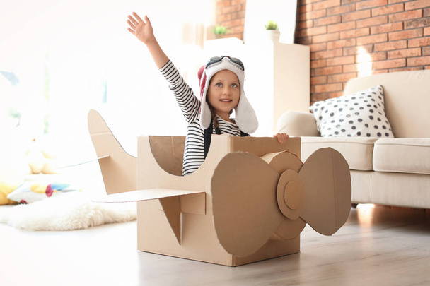 Adorable little child playing with cardboard plane at home - Fotoğraf, Görsel