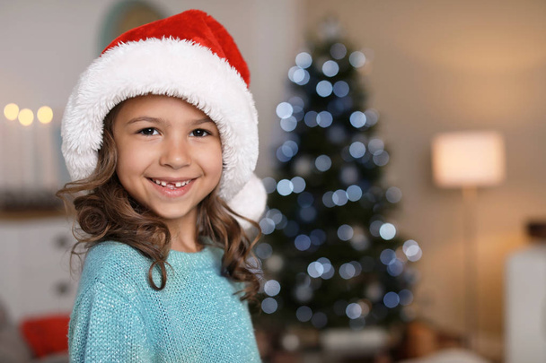 Cute little child in Santa hat at home. Christmas celebration - Fotó, kép