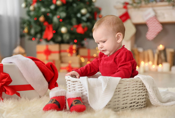 Cute baby sitting in basket at home. Christmas celebration - Foto, imagen