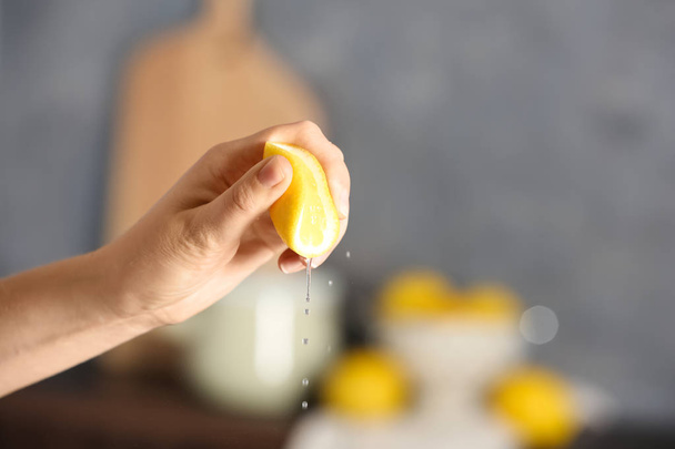 Young woman squeezing lemon on blurred background - Foto, Imagen