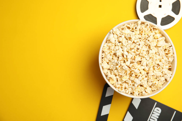 Flat lay composition with popcorn, film reel and clapperboard on color background - Foto, Imagen