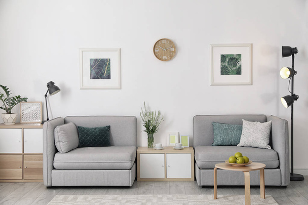 Interior moderno da sala de estar com poltronas confortáveis perto da parede branca
 - Foto, Imagem