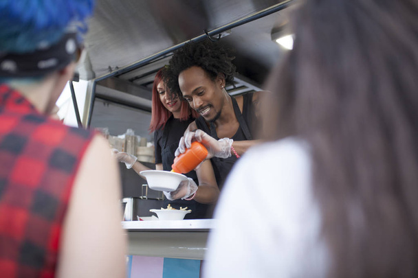 young woman and redhead working on a food truck with an afro man - Fotoğraf, Görsel