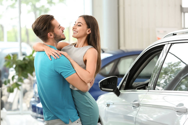 Happy couple buying new car in salon - Foto, imagen