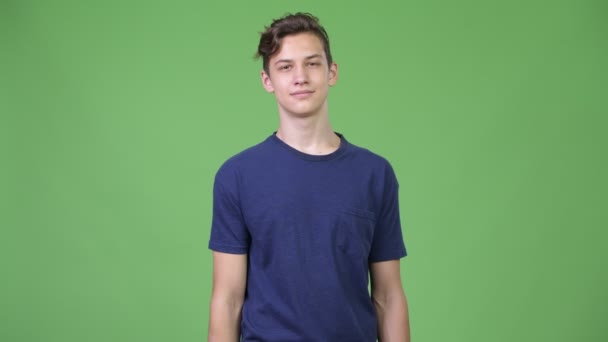 Młody przystojny chłopak nastoletnich wskazując na aparat - Materiał filmowy, wideo