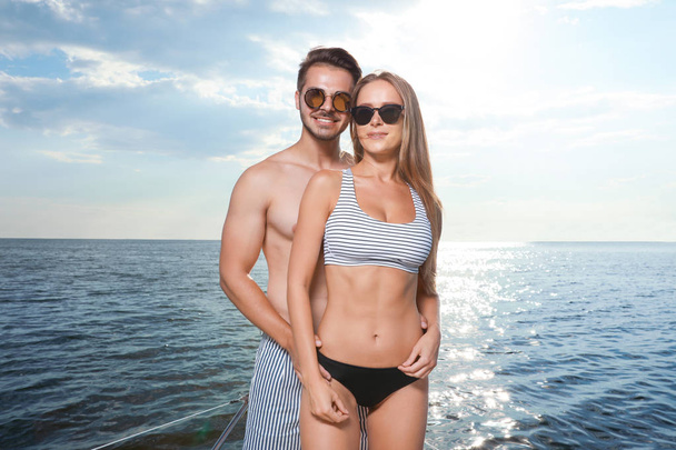 Young man and his beautiful girlfriend in bikini on yacht. Happy couple on vacation - Photo, Image
