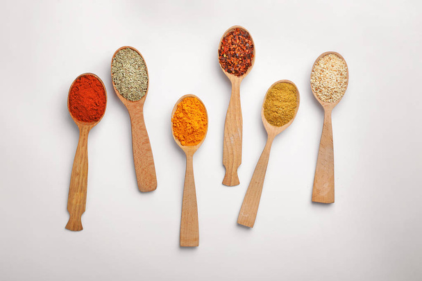 Composition with different aromatic spices in wooden spoons on white background - 写真・画像