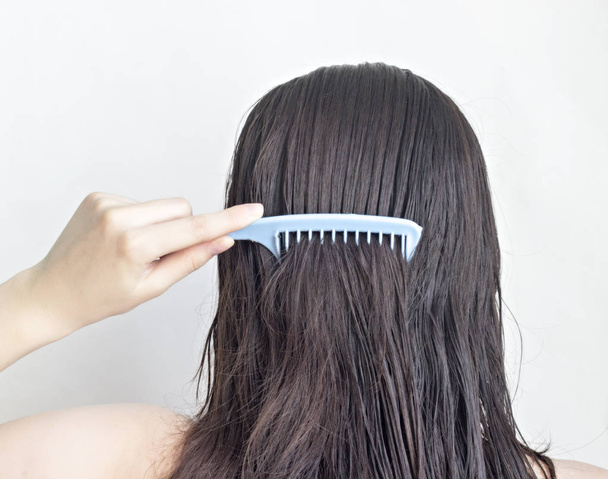 Girl combs long black hair comb, rear view, white background - Foto, immagini