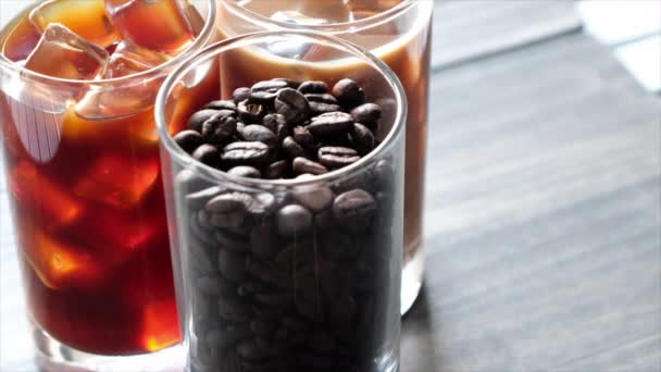 Μαύρο παγωμένο καφέ, κρύο latte και φασόλια πέρα από πίνακα - Πλάνα, βίντεο