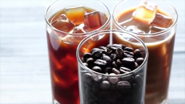 Zwarte iced koffie, koud latte en bonen boven tafel - Video