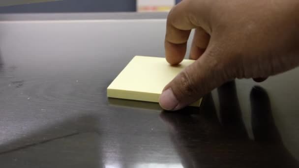 abgeschnittene Ansicht eines Mannes, der zu Hause Papieraufkleber vom Holztisch nimmt - Filmmaterial, Video