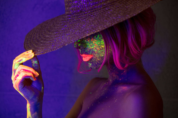 junge Frau mit Hut mit fluoreszierender Farbe auf Lippen und Gesicht - Foto, Bild